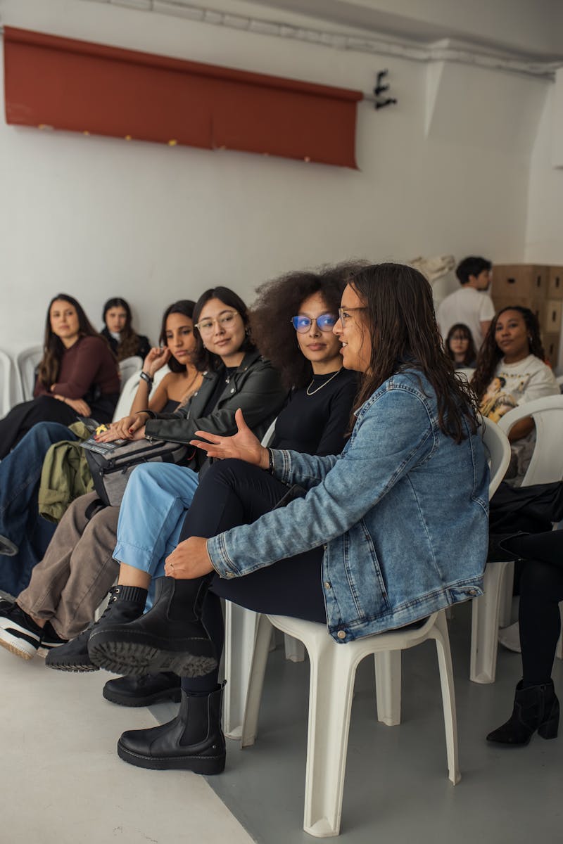 A diverse group of adults attentively sitting indoors during an engaging workshop session.