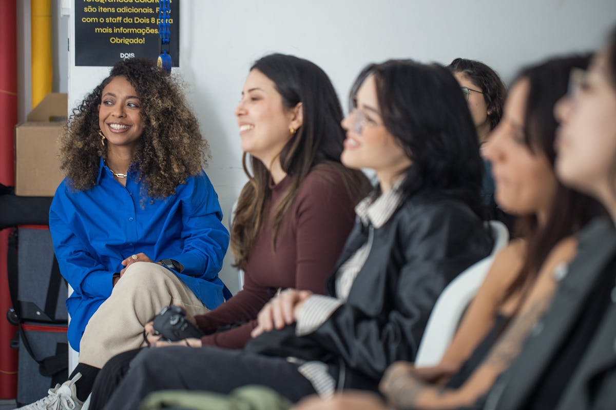 A group of diverse women engaged in a casual learning environment, smiling and attentive.